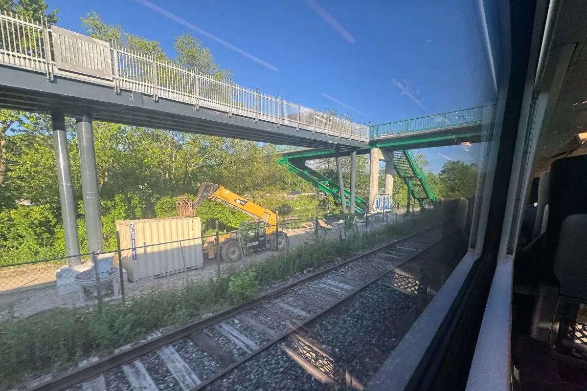 Railroad tracks with pedestrian bridge and trees in background