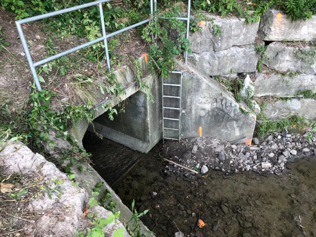 Concrete culvert and shallow stream with large rocks