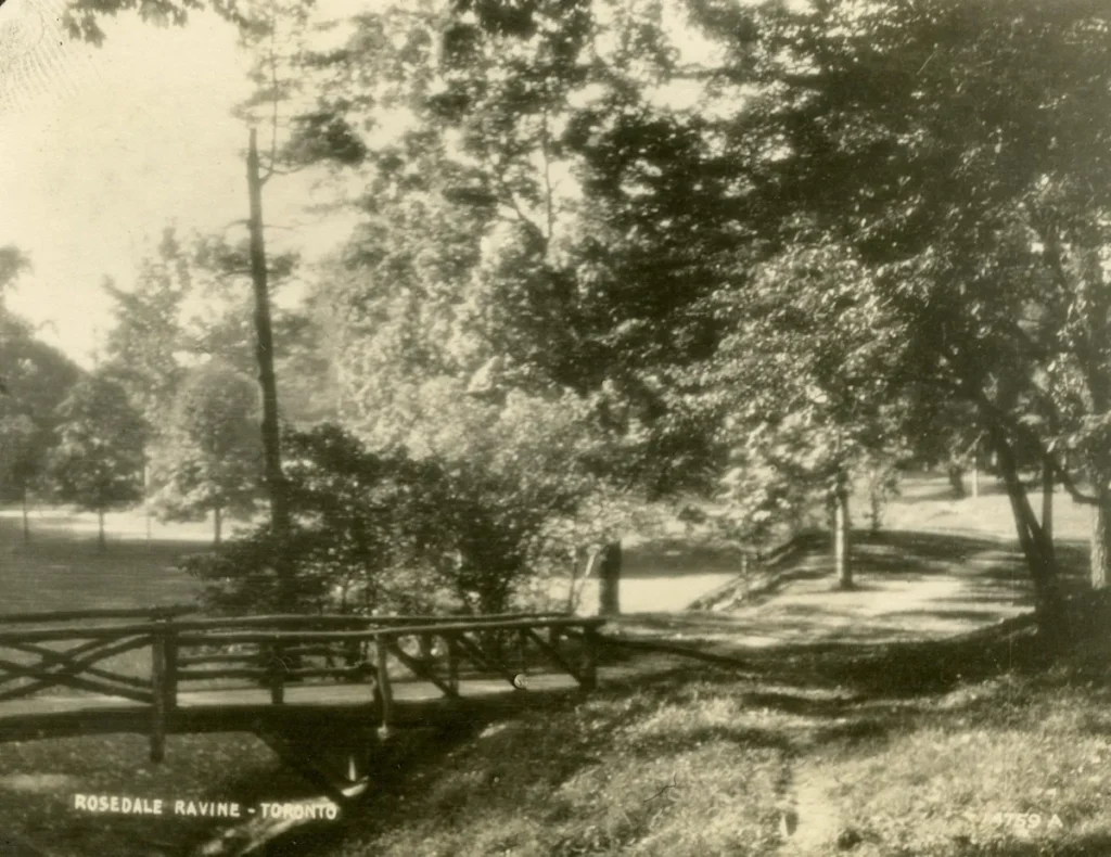 Sepia-toned photograph of a small wooden bridge over a stream in a leafy park, captioned &ldquo;Reservoir Park, Tonawanda.&rdquo;
